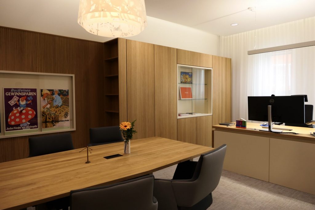 Großes Büro mit Schreibtisch, Besprechungstisch und moderner Einrichtung.