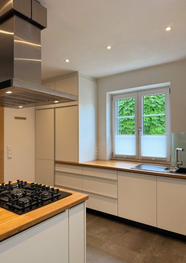 Helle moderne Küche mit warmen Eichenholzplatten.