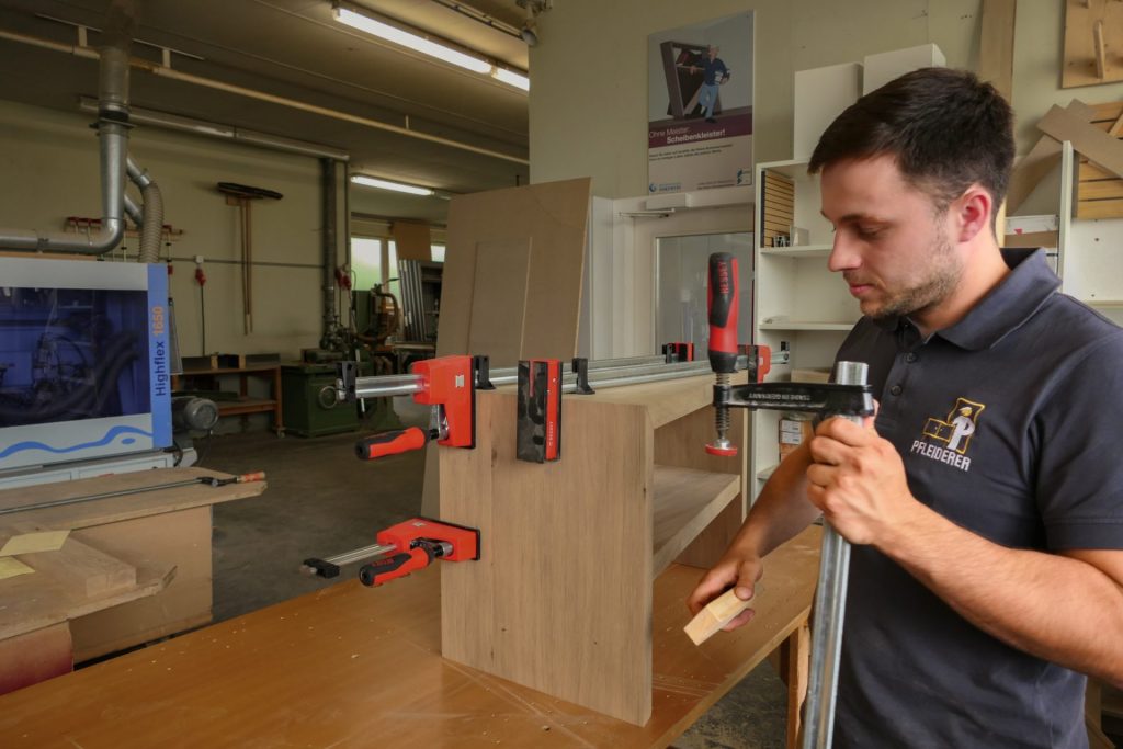 Mann arbeitet an Holzprojekt in Werkstatt.