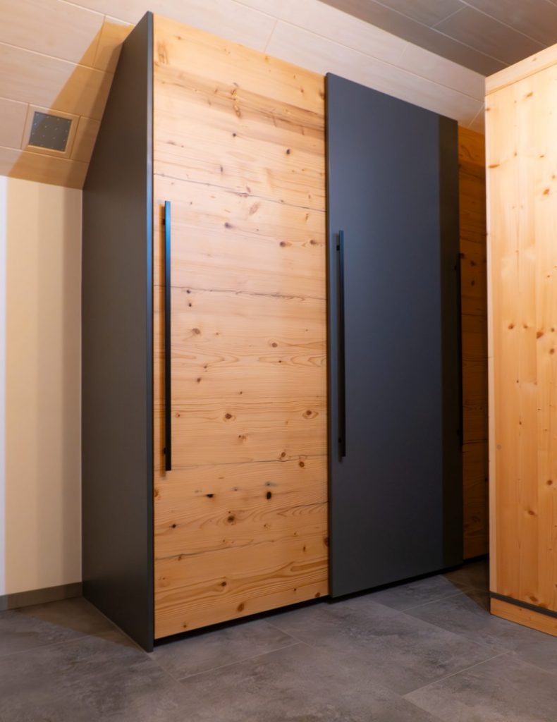 Einbauschrank für eine Nische mit anthrazitgrauen Elementen und Eichenfronten, ausgestattet mit großen schwarzen Griffen.