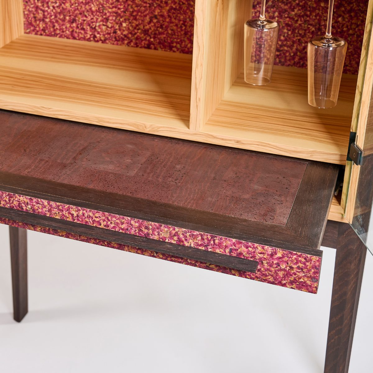 Hochwertiger Barschrank aus Olivenholz mit geräucherter Eiche im Barauszug und kunstvoll gestalteten Flora‑Fronten als stilvolle Akzente.