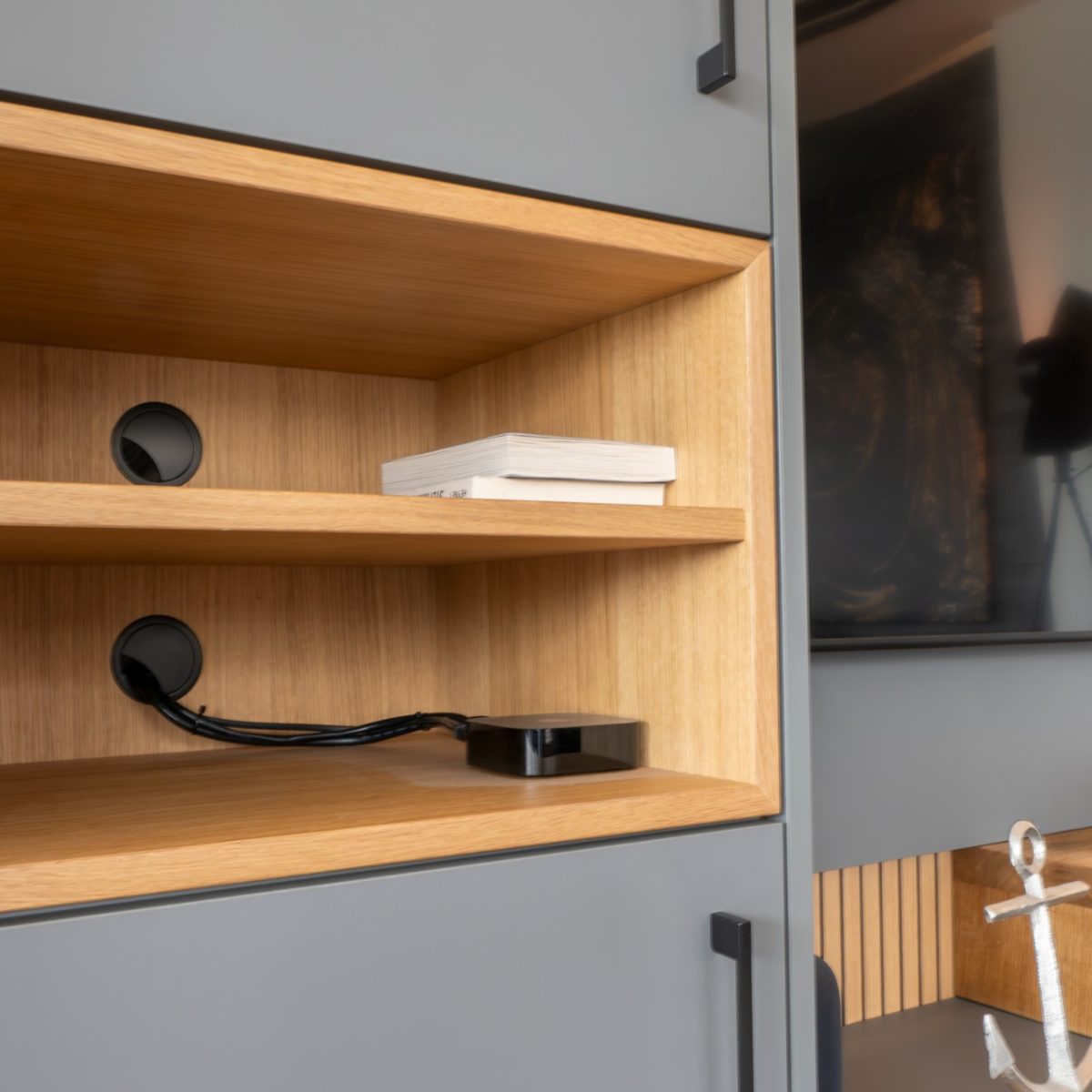 Stilvolles Wohnzimmerensemble mit grauem Sideboard und passenden Eichenholzdetails; im Hintergrund eine Wand aus beleuchteten Holzpaneelen, die dem Raum Struktur und ein hochwertiges Ambiente geben.