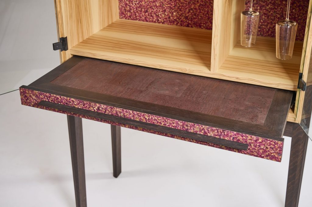 Barschrank aus edlem Olivenholz mit einem ausziehbaren Barfach in geräucherter Eiche und Fronten im Flora‑Design.