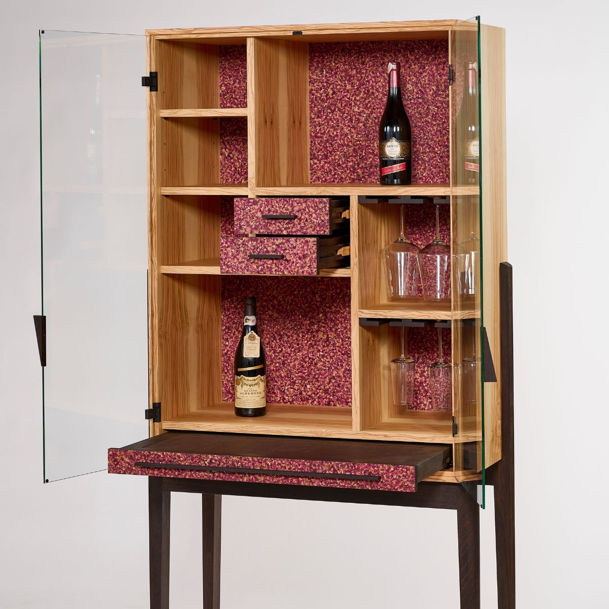 Hochwertiger Barschrank aus Olivenholz mit geräucherter Eiche im Barauszug und kunstvoll gestalteten Flora‑Fronten als stilvolle Akzente.