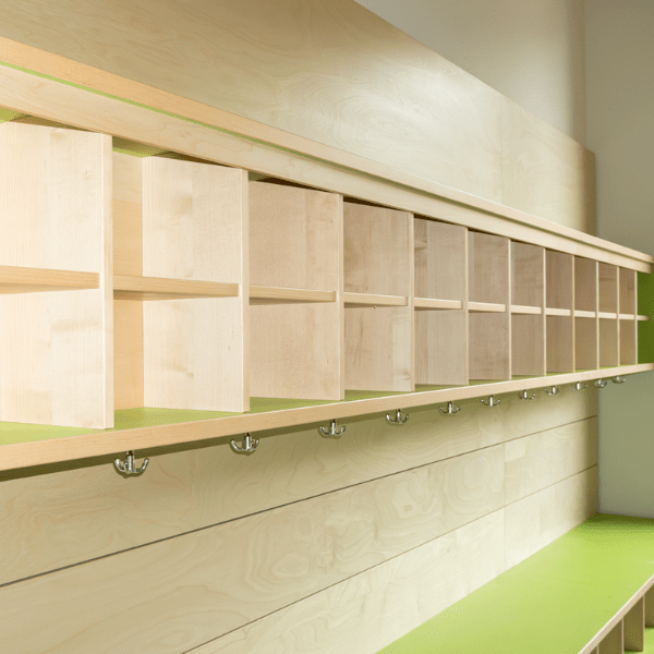 Kita‑Garderobe mit Sitznischen für Kinder, Ablageflächen für Schuhe und Haken für Jacken.